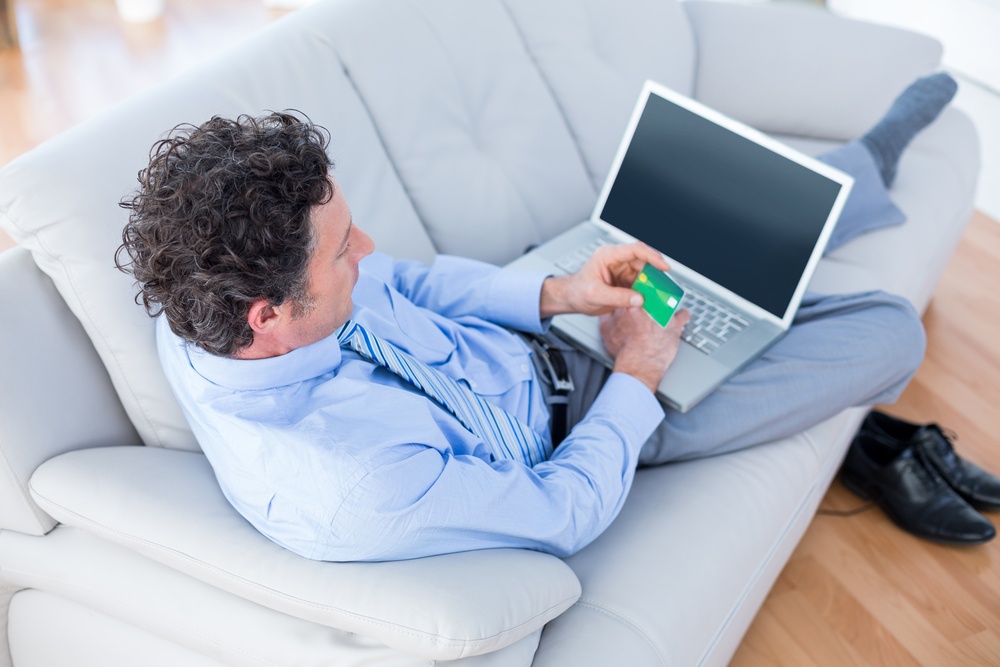 Businessman doing online shopping on couch in living room
