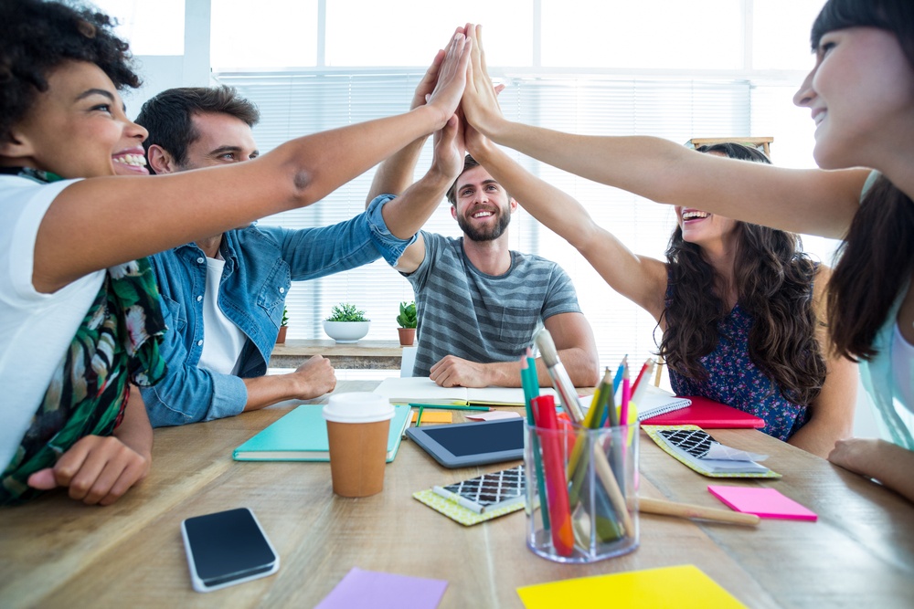 Creative business team putting hands together at the office.jpeg Creative business team putting hands together at the office.jpeg